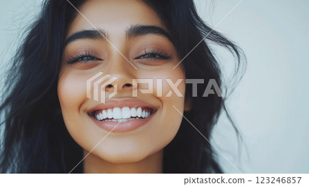 Radiant smile on a youthful face, showcasing natural beauty and healthy teeth. Warm skin tone with dark hair frames the face beautifully. Radiant smile on a youthful face, showcasing natural beauty and healthy teeth. Warm skin tone with dark hair frames the face beautifully. 123246857