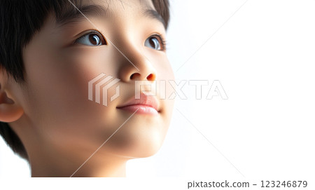 A child gazes upwards with wonder, their clear eyes reflecting curiosity and hope in a serene, brightly lit environment. 123246879