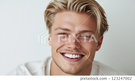 Smiling blond man with modern hairstyle. Radiating joy and confidence, he presents a fresh and engaging look. Portrait on neutral background. 123247002