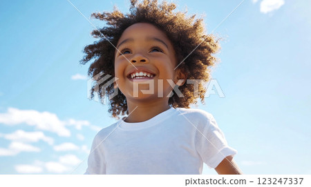 Smiling child gazing upwards with joy, standing under a clear blue sky with scattered clouds on a bright, sunny day. Smiling child gazing upwards with joy, standing under a clear blue sky with scattered clouds on a bright, sunny day. 123247337
