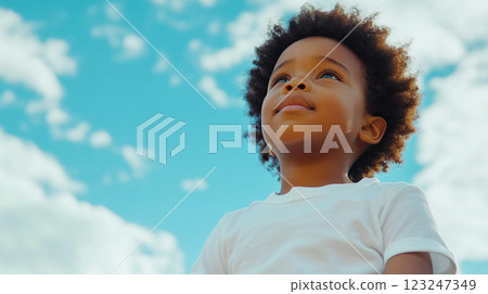Young boy looking up at the blue sky filled with clouds, showcasing a sense of wonder, imagination and dreams of the future. Young boy looking up at the blue sky filled with clouds, showcasing a sense of wonder, imagination and dreams of the future. 123247349