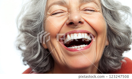 Joyful Mature Woman: Eyes closed, mouth wide open, showing perfect teeth in a sincere laugh. The woman has gray hair in a bright studio shot. 123247508