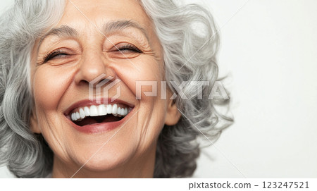 Radiant senior woman with silver hair, beaming with joy and bright white teeth, showcasing a picture of health and happiness. 123247521