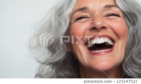 Radiant joy on display. A woman with silver hair and a bright, open-mouthed laugh, full of unadulterated happiness and contagious energy. 123247522