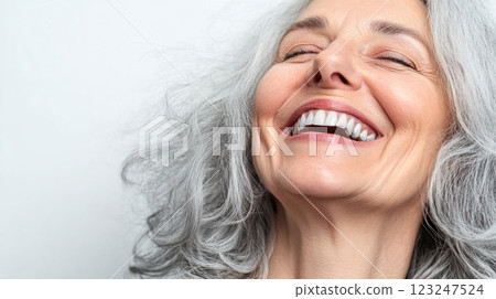 Radiant smile of a mature woman with flowing silver hair, her eyes closed in joyous laughter against a bright background. Radiant smile of a mature woman with flowing silver hair, her eyes closed in joyous laughter against a bright background. 123247524