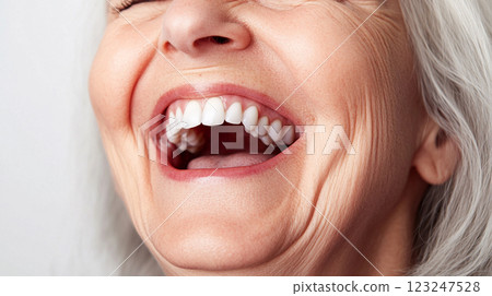 An older woman laughs heartily, showcasing her white teeth and facial wrinkles that are visible as she smiles, showing pure joy. An older woman laughs heartily, showcasing her white teeth and facial wrinkles that are visible as she smiles, showing pure joy. 123247528
