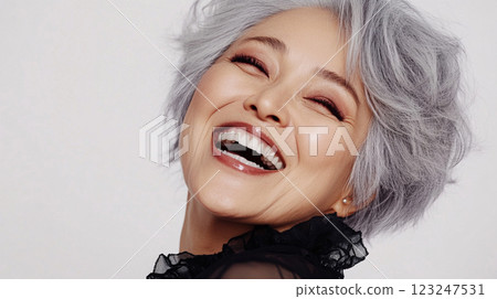 Radiant woman with silver hair joyfully smiling. Close-up showcasing her expressive face against a clean, bright backdrop. Authentic charm. 123247531