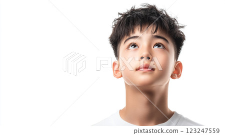 A young boy with dark hair stares upwards with an expression of hope, wonder, and curiosity. The background is clean, minimal, and white. A young boy with dark hair stares upwards with an expression of hope, wonder, and curiosity. The background is clean, minimal, and white. 123247559