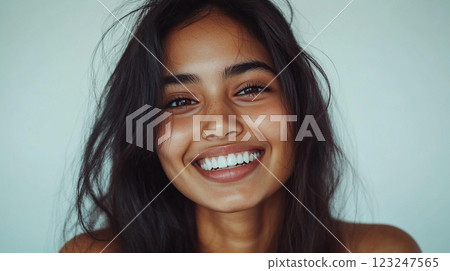 Radiant portrait of a woman with a warm smile, showcasing natural beauty and confidence. Her dark hair and bright teeth create a striking contrast. 123247565