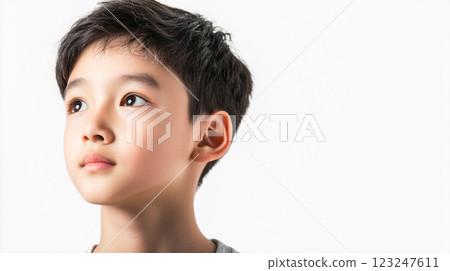 Young Asian boy with dark hair and light skin gazes off into the distance on a clean white background, thinking or imagining the future. 123247611