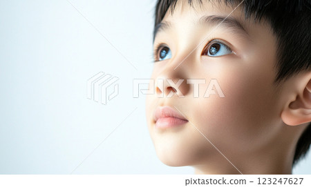 Child with hopeful gaze looking upwards towards light, his face in profile against a bright, neutral background. innocent expression. Child with hopeful gaze looking upwards towards light, his face in profile against a bright, neutral background. innocent expression. 123247627