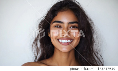 Radiant woman with beautiful smile, shiny dark hair. A portrait of warmth & charm against a plain backdrop; capturing her natural elegance. 123247639