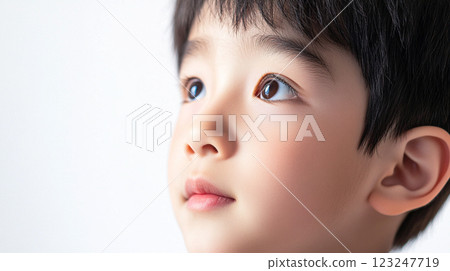 Close-up of a young boy with dark hair, looking upwards with a thoughtful expression against a bright, clean, white background. Close-up of a young boy with dark hair, looking upwards with a thoughtful expression against a bright, clean, white background. 123247719