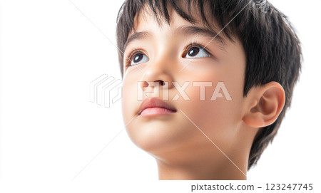 Boy looks upward with wonder, eyes wide with curiosity, bathed in soft, even light. Portrait captures innocence and youthful contemplation. 123247745