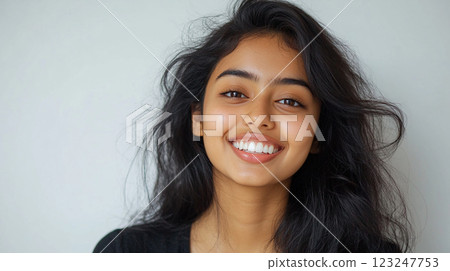 Radiant smile portrait of a young woman with long, dark, flowing hair, showcasing natural beauty against a neutral background. Radiant smile portrait of a young woman with long, dark, flowing hair, showcasing natural beauty against a neutral background. 123247753