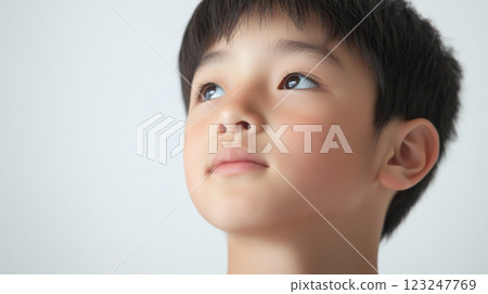 Focused young boy gazes upward with a hopeful expression, suggesting dreams and aspirations. A portrait of innocence and anticipation. 123247769