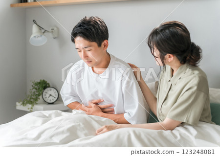 A man suffering from abdominal pain and a worried woman/couple in the morning in the bedroom 123248081