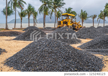 bulldozer at a construction site on sandy beach by the sea in a tropical resort in Asia. Focus on the gravel pile bulldozer at a construction site on sandy beach by the sea in a tropical resort in Asia. Focus on the gravel pile 123248123