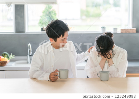 A depressed/crying woman/wife/man comforting her/husband/boyfriend in the dining room (quarrel/marital quarrel) A depressed/crying woman/wife/man comforting her/husband/boyfriend in the dining room (quarrel/marital quarrel) 123249098