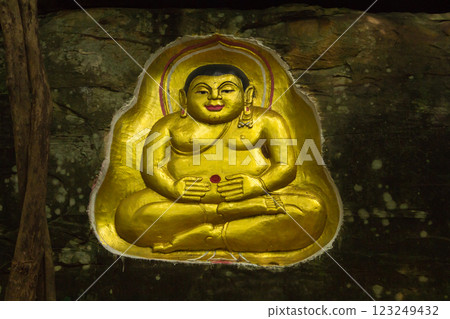 Buddha statue carved into a cliff. A golden Buddha statue is carved into a cliff face. 123249432