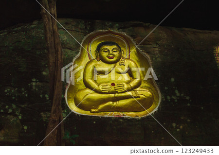 Buddha statue carved into a cliff. A golden Buddha statue is carved into a cliff face. 123249433
