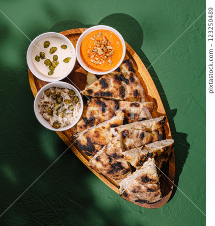 Plate of traditional flatbread with sides served on wooden platter 123250489