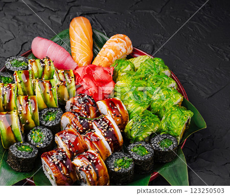Sushi platter featuring assorted rolls and sashimi on a dark surface Sushi platter featuring assorted rolls and sashimi on a dark surface 123250503