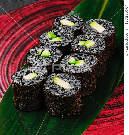 Unique black sushi rolls served on an elegant red plate Unique black sushi rolls served on an elegant red plate 123250504