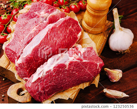 Fresh cuts of beef surrounded by herbs and vegetables Fresh cuts of beef surrounded by herbs and vegetables 123250536