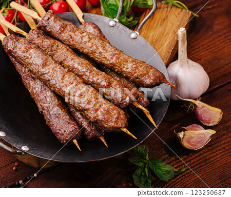 Grilled skewers of tender meat on a wooden table with vegetables 123250687
