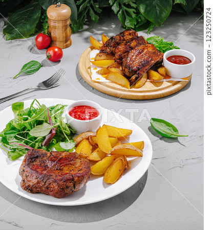 Delicious grilled ribs and steak served with potatoes and salad Delicious grilled ribs and steak served with potatoes and salad 123250724