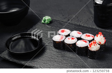 Sushi rolls arranged on a textured black plate with wasabi 123250738