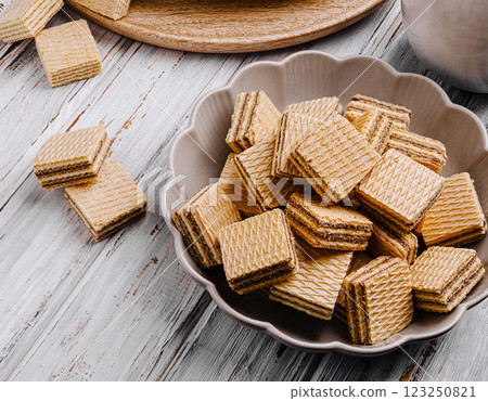 Crunchy wafers stacked in a decorative bowl on a rustic table 123250821