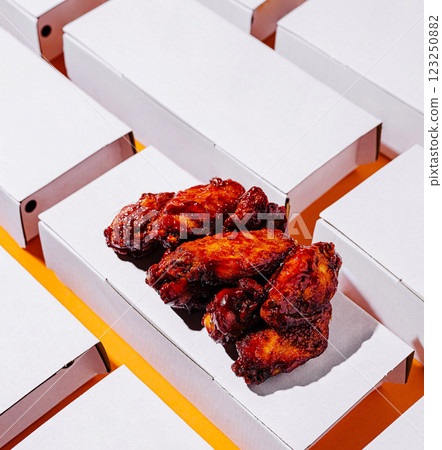 Juicy chicken wings in white boxes on an orange background 123250882