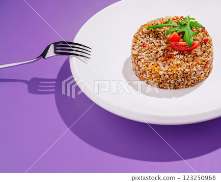 buckwheat salad on a white plate with a purple backdrop 123250968