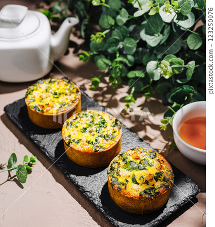 Savory mini quiches with spinach and herbs on a rustic table Savory mini quiches with spinach and herbs on a rustic table 123250976