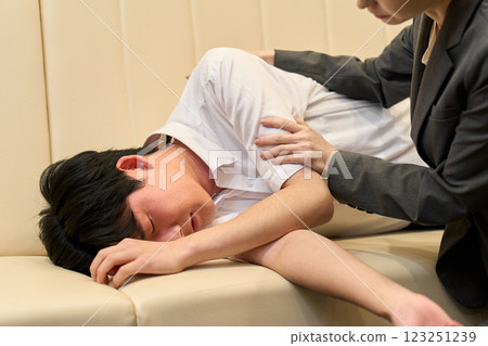 一名男子因酒精中毒而暈倒，一名女子撫摸著他 123251239