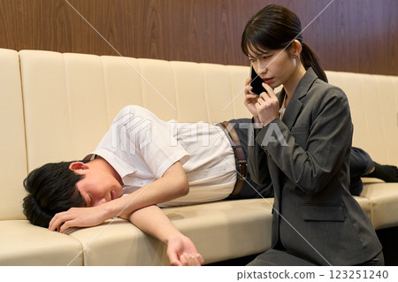 A woman talking on the phone with a man who collapses from alcohol poisoning A woman talking on the phone with a man who collapses from alcohol poisoning 123251240