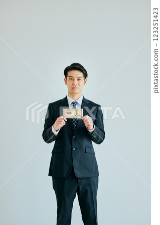 A young man in his twenties holding a 10,000 yen bill 123251423