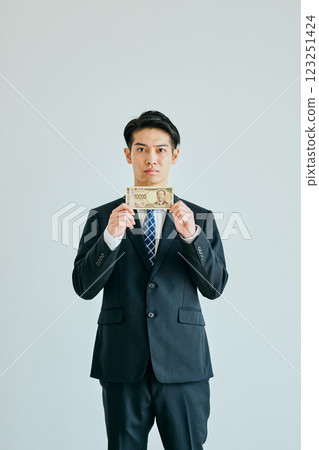 A young man in his twenties holding a 10,000 yen bill 123251424