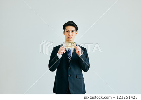 A young man in his twenties holding a 10,000 yen bill 123251425