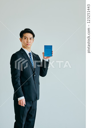 一名 20 多歲的年輕人拿著一本退休金簿 123251443