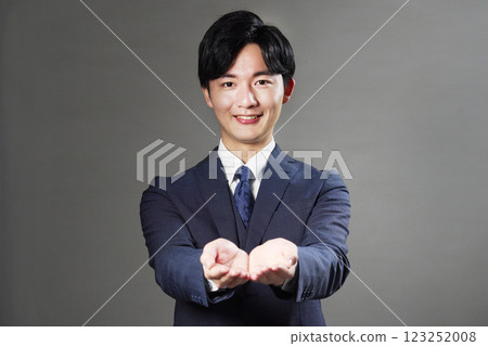 Businessman holding out both hands on black background 123252008