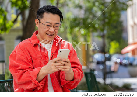 Asian middle-aged man using smartphone typing text messages in social media application online Asian middle-aged man using smartphone typing text messages in social media application online 123252189