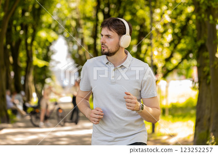 Athletic fitness sport jogger man training marathon run listening music in headphones, morning park Athletic fitness sport jogger man training marathon run listening music in headphones, morning park 123252257