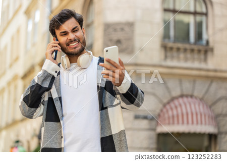 Stressed Indian man talking screaming on mobile phones having conflict quarrel complaint on street Stressed Indian man talking screaming on mobile phones having conflict quarrel complaint on street 123252283