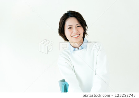 Young woman sitting on a chair in front of a wall 123252743