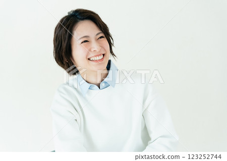 Young woman sitting on a chair in front of a wall 123252744