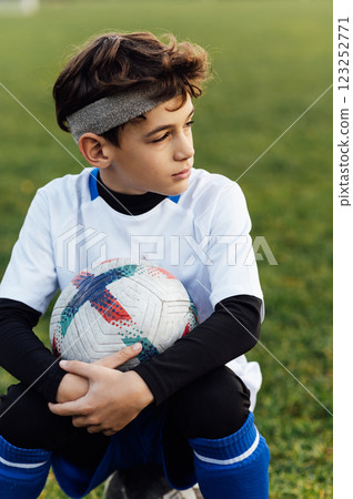 Young football player in white uniform posing on football field. School sports club. Young football player in white uniform posing on football field. School sports club. 123252771