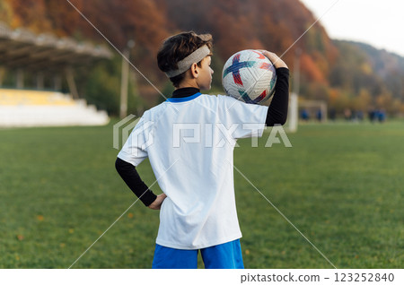 Young football player in white uniform posing on football field. School sports club. Young football player in white uniform posing on football field. School sports club. 123252840